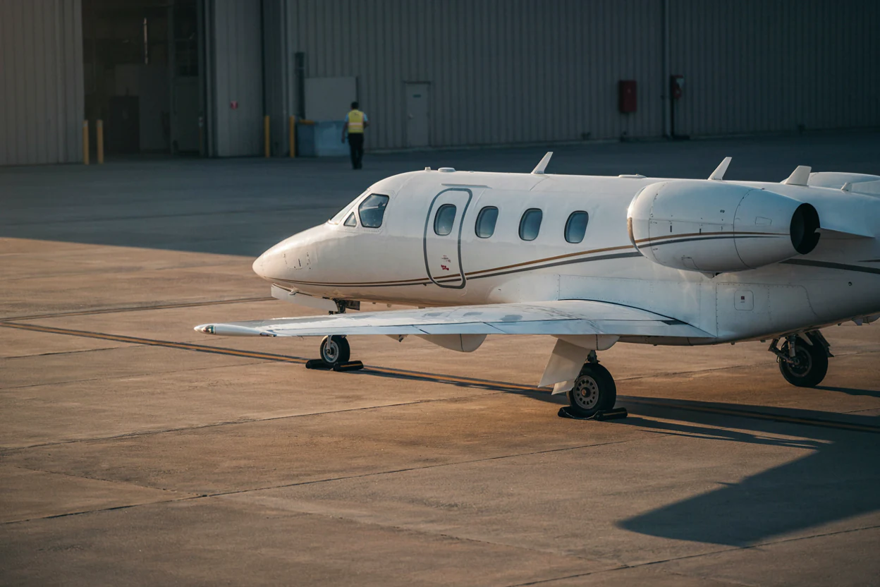 Ground crew beside a light jet outside its hangar